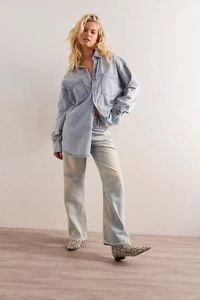 Detail of light blue washed denim shirt and matching straight jeans with snake pattern boots