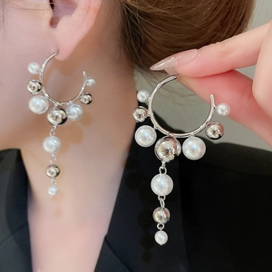 Macro detail of geometric C-shaped earrings with pearls and silver fringe tassels