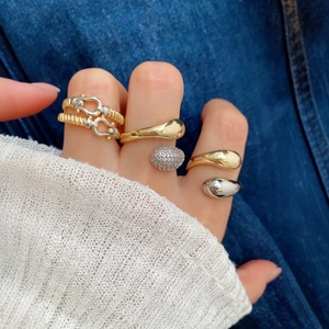 Close-up of stacked gold and silver horseshoe rings and crystal bands on a model hand