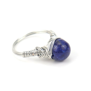 Detailed view of silver wire wrapped ring with a blue gemstone bead centerpiece