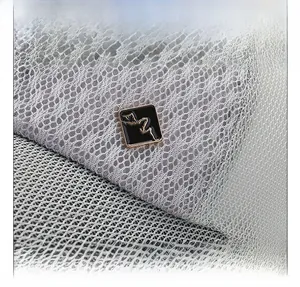 Detail of light gray mesh baseball cap showing breathable honeycomb lace and metal logo