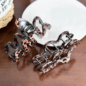 Elegant leopard print acetate hair claw clips displayed on a rustic wooden tabletop