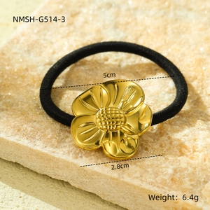 Detail showing dimensions of gold flower hair tie with black elastic band on stone