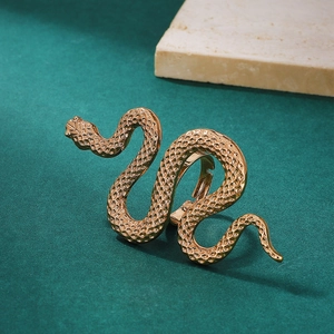 Detail of golden snake ring with textured scales on a dark green surface with white stone