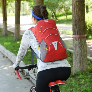 Red outdoor cycling backpack with reflective strips and breathable mesh shown in nature