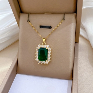 Macro view of gold rectangle emerald pendant necklace with halo of white zircons