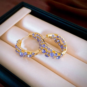 Detailed macro view of gold plated hoop earrings featuring sparkling purple rhinestones