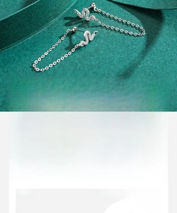 Detailed macro view of silver snake earrings featuring green zircon eyes and long chain tassels
