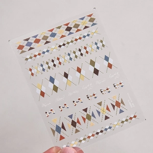 Close-up of retro argyle nail art stickers with vintage patterns and bow designs