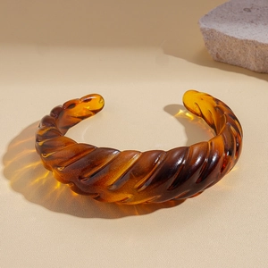 Close-up of amber resin open bangle featuring spiral textures and translucent finish