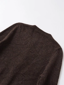 Detail view of the ribbed round neckline and shoulder of a dark brown knit sweater