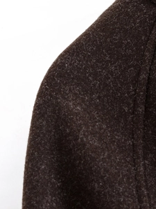 Close-up of deep brown wool coat texture showing high-quality stitching and fabric