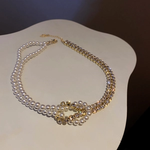 Detail of elegant gold chain necklace with rhinestones and white pearls in luxury style
