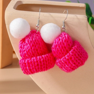 Detailed view of rose red knitted hat earrings with soft white pompom and silver hooks