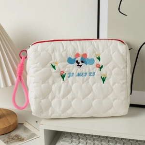 Heart quilted cosmetic bag with blue puppy embroidery and pink zipper on a desk
