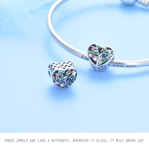 Macro view of S925 silver heart tree charm with colorful zircons on a snake chain bracelet