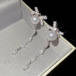 Silver bow earrings with sparkling diamonds and long pearl tassels in a jewelry box