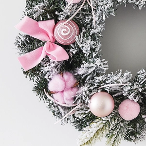 Couronne de Noël rose avec épines de pin floquées de blanc, nœuds et bonbons déco