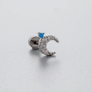 Clou d'oreille croissant de lune argenté avec zircon bleu et cristaux sur fond gris