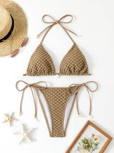 Detail of light brown seersucker bikini with seashell accents and side ties on white background