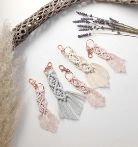 Detail view of five handmade macrame tassels with rose gold lobster clasps in soft colors