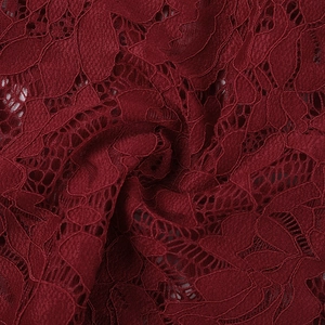 Close-up of wine red lace fabric with intricate floral patterns and hollow knit detail