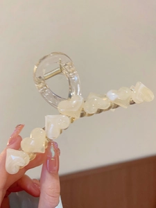 Detail shot of a large transparent hair claw clip featuring creamy resin hearts
