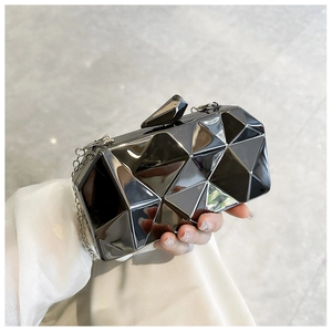 Detail of glossy black geometric faceted acrylic clutch bag with silver chain strap