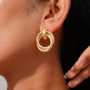 Close-up of minimalist gold-tone interlocking double loop earrings on model ear