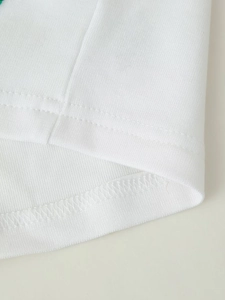 Detail shot of the white beaded crop top hem featuring reinforced double-needle stitching