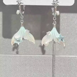 Asymmetric silver fishtail dangle earrings with green pearls and star tassel detail