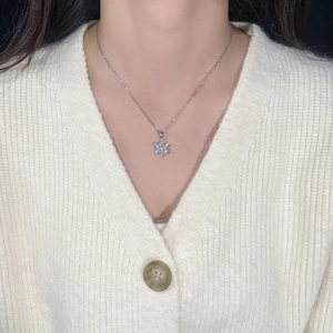 Close-up of a silver snowflake pendant necklace with zircons worn on a white knit sweater