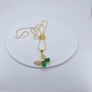 Detail of gold butterfly pendant with green pear-shaped stones and tiny white zircons