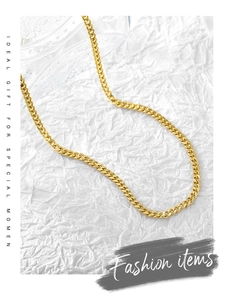 Detail view of a gold Cuban link chain necklace on textured white background with gift text