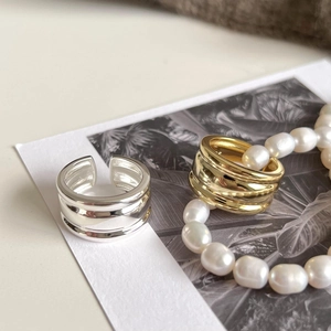 Artistic close-up of minimalist gold and silver open rings on decorative card