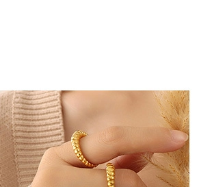 Macro shot of gold twisted croissant rings stacked on finger with a vintage aesthetic