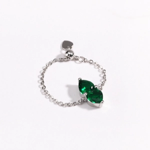 Detail of adjustable chain ring with green pear-cut gemstones and a small heart pendant