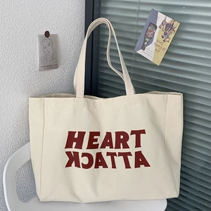 Detail of off-white canvas tote bag with red Heart Attack print on a white chair