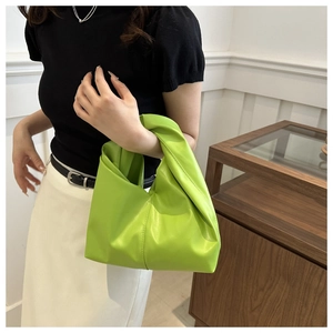 Dettaglio della borsa verde brillante con manico a nodo unico e morbida ecopelle plissettata