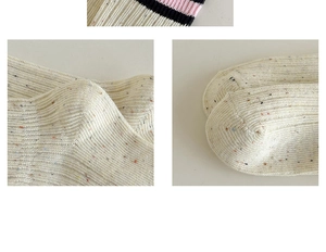 Dettagli macro di calze in maglia crema con puntini colorati e polsini a righe