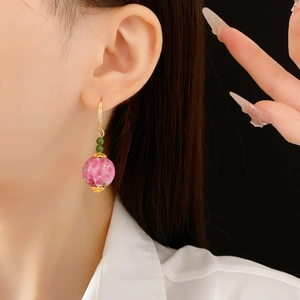Nahaufnahme von rosa Marmorperlen-Ohrringen mit Goldhaken und funkelnden Zirkonia