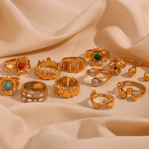 Flat lay of vintage 18K gold plated rings with zircon flower and crown designs on silk
