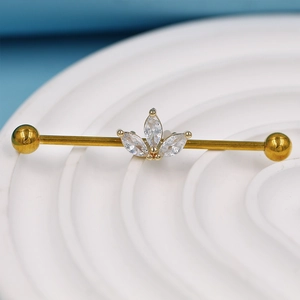 Gros plan d'un piercing industriel doré avec zircons marquise sur un support céramique