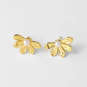 Elegant gold flower stud earrings with central pearl accents on a minimalist background