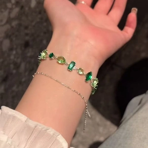 Close-up of a double-layered bracelet with vibrant green stones on a model's wrist