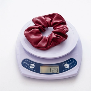 Close-up of a burgundy PU leather scrunchie showing detailed texture and 12.9g weight