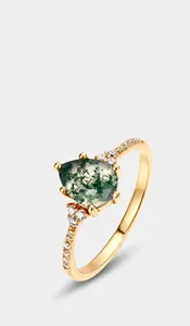 Detailed macro view of pear-cut green moss agate ring with gold band and diamonds