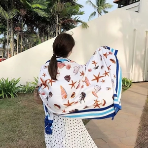 Detail of beach towel with starfish and shell patterns worn over shoulders outdoors