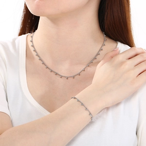 Gros plan sur l'ensemble collier et bracelet en titane argenté avec perles pendantes