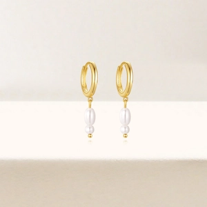 Detailed view of double pearl pendants on golden hoops with a minimalist vertical design